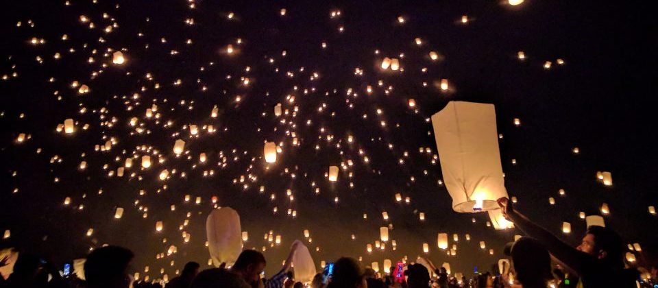 Photo of people releasing paper lanterns into the sky at night