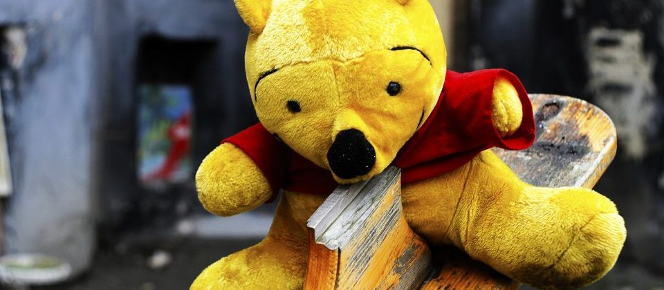 Photo of a dirty, worn stuffed animal, likely Winnie the Pooh