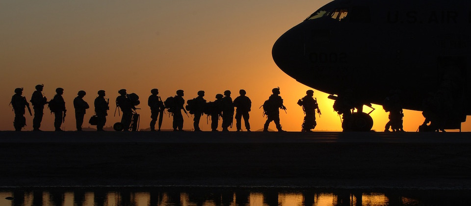 Photo of soldiers standing near an aircraft at sunset