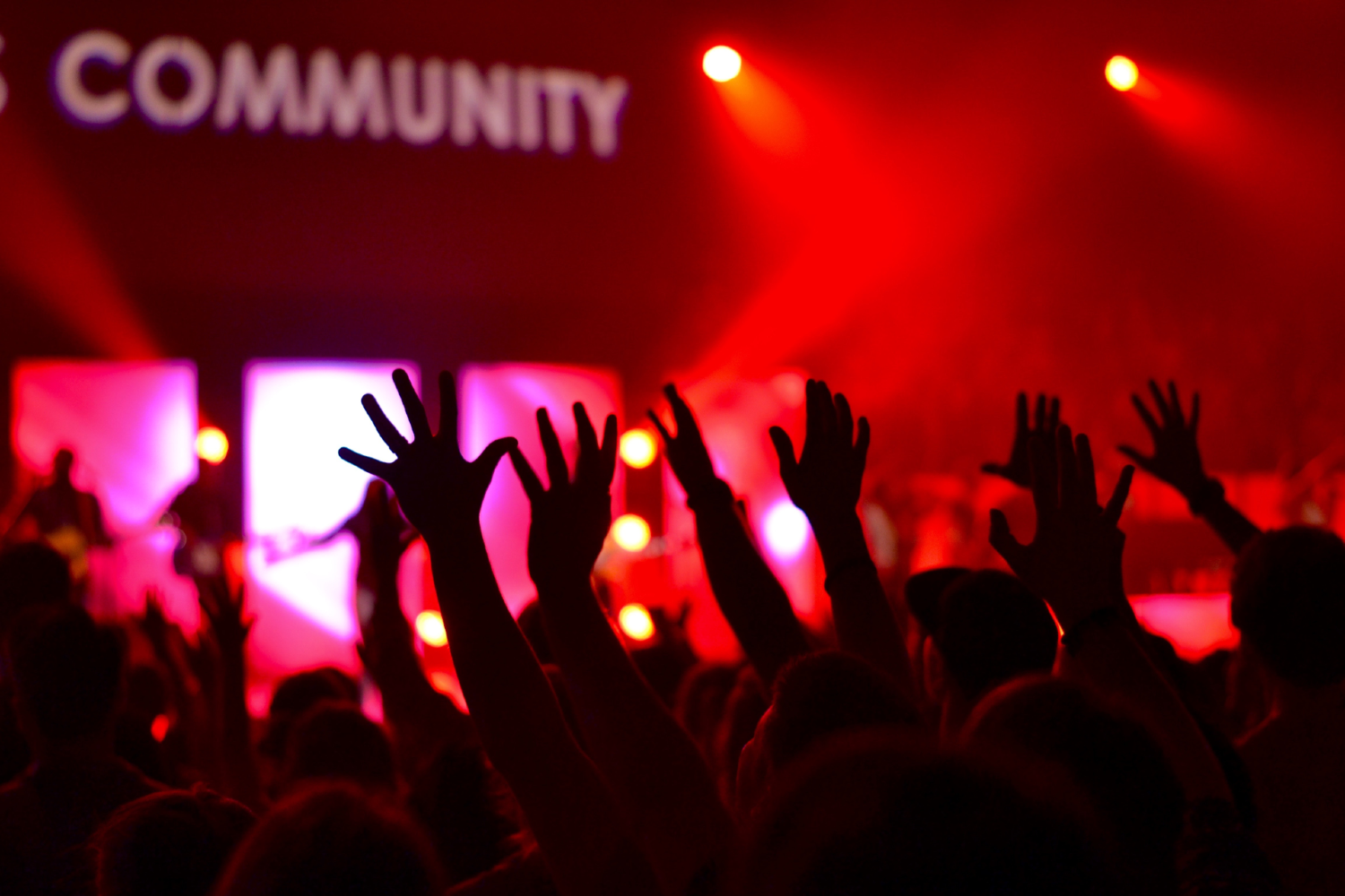 hands reaching toward word community with a red lighting background